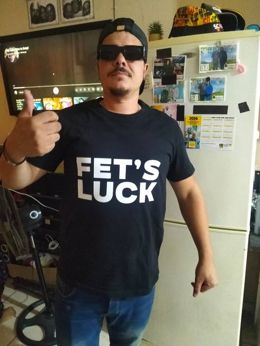 Man wearing a navy t-shirt printed Fet's Luck in bold white lettering