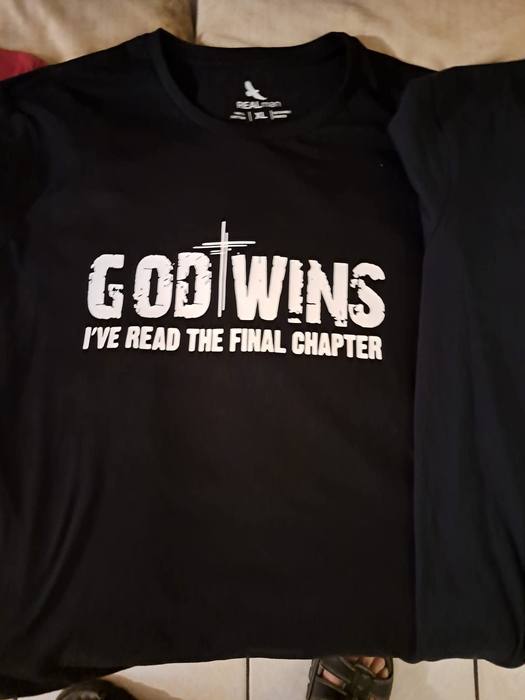 Black t-shirt printed God Wins, I have read the final chapter, with a cross in the lettering