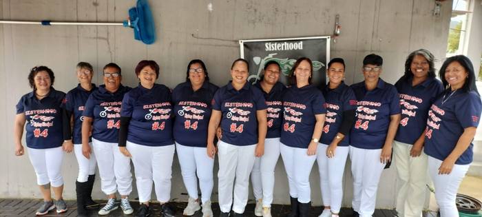Twelve members of a Sisterhood group in matching navy printed shirts and white trousers