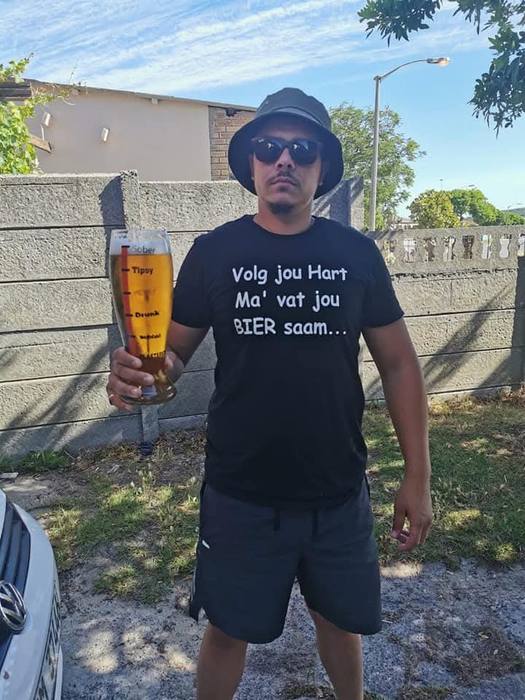 Man in a black t-shirt printed Volg jou Hart Ma vat jou Bier saam, holding a printed beer glass