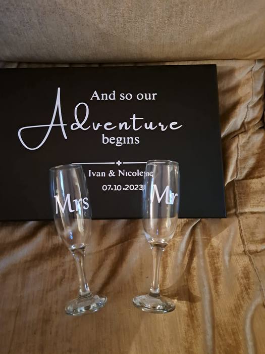 Wedding board reading And so our adventure begins, beside champagne flutes printed Mr and Mrs